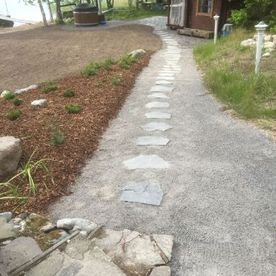 Kivilaatoista rakennettu polku mökin saunalle
